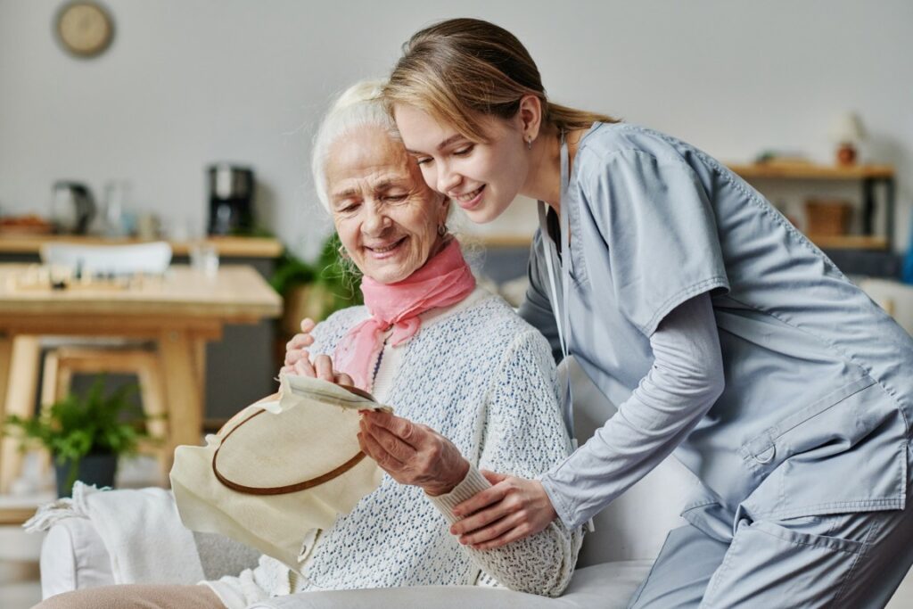 Senior woman showing her embroidery to caregiver